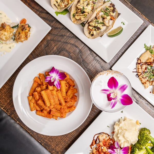 An overhead view of various American dishes from Catch 13 RVC, including pasta, tacos, and seafood.