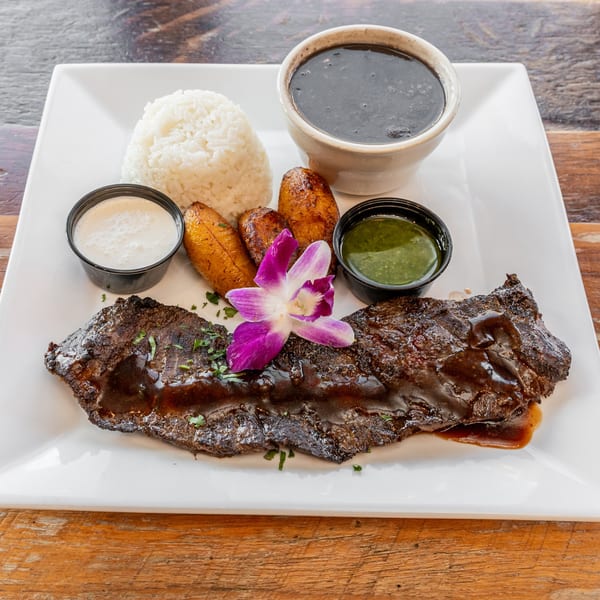Catch 13 RVC's American cuisine: steak with rice, black beans, plantains, and sauces, garnished with an orchid.